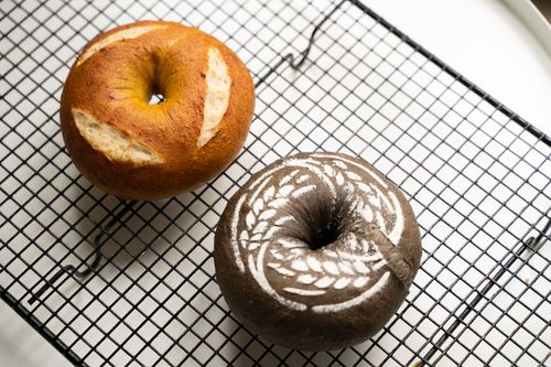 Free Close-up of two artisanal bagels with unique designs on a cooling rack. Stock Photo