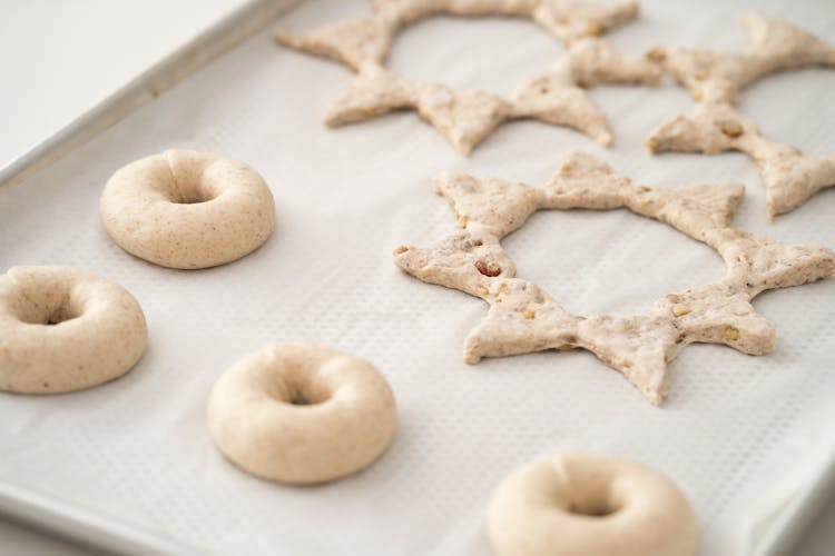 Raw Dough Bagels And Star Shape Cakes On A Baking Tray