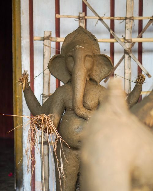 Free Close-up of a clay Ganesha sculpture under construction with bamboo support, showcasing intricate artistry. Stock Photo
