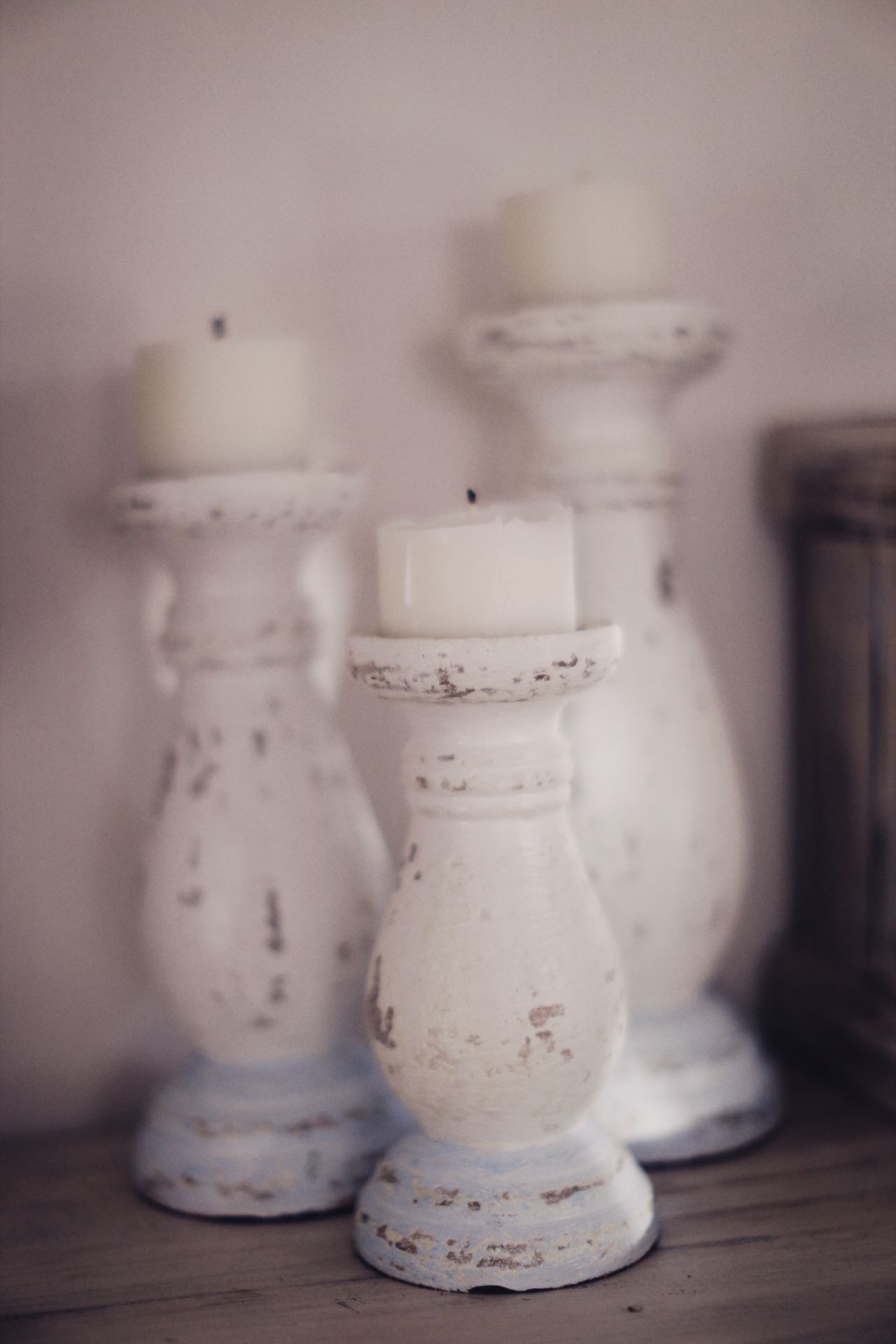 Three white distressed wooden candle holders with short white candles