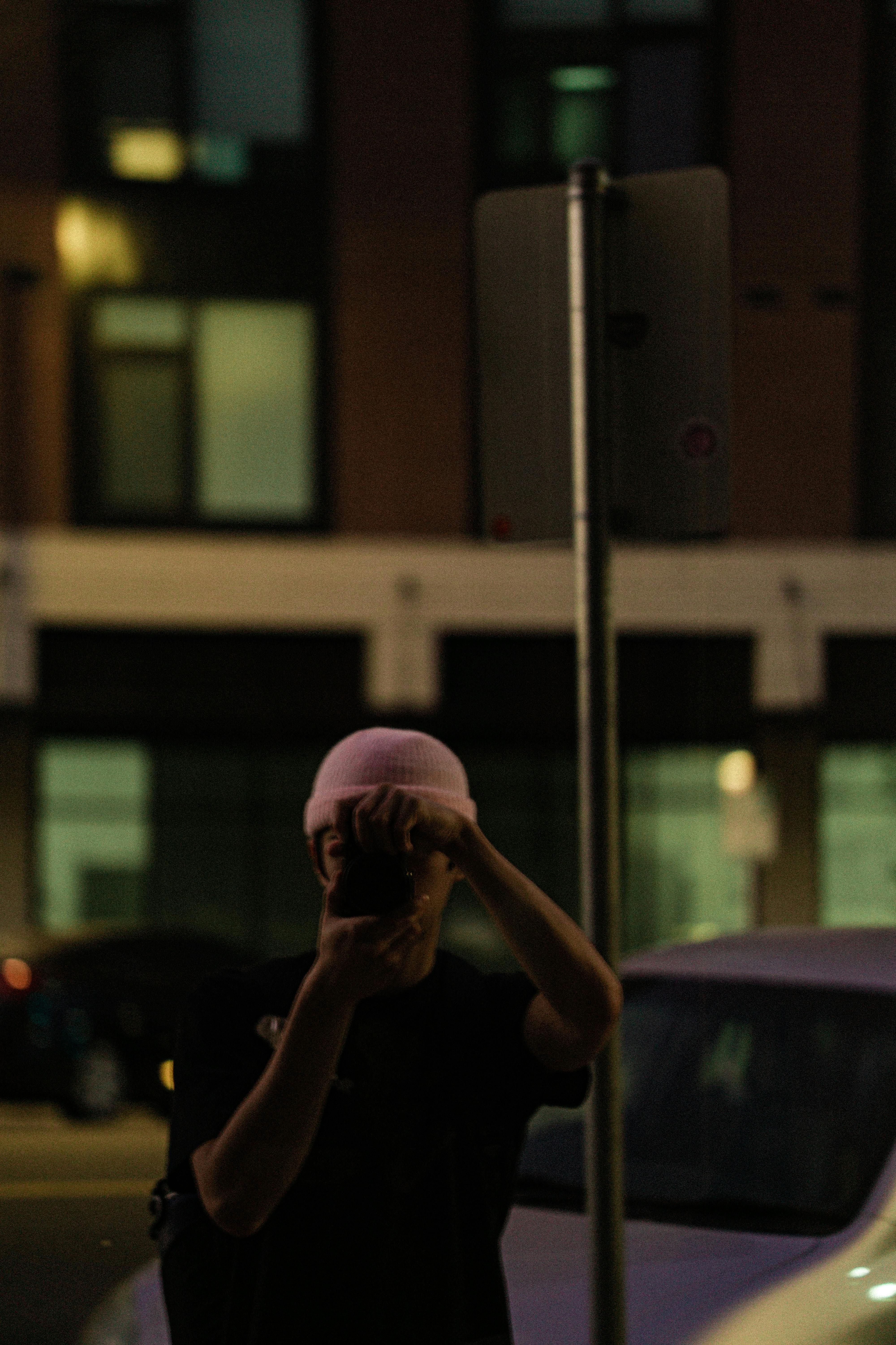 Free Silhouette of a person taking a photo at night on a city street. Stock Photo