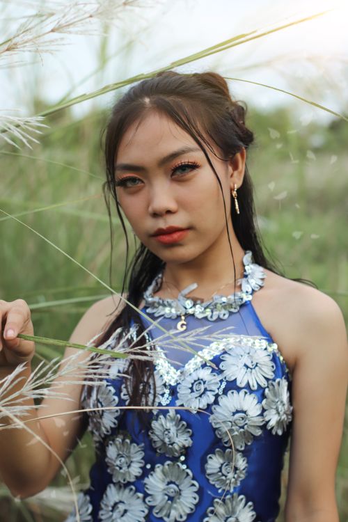 Free Portrait of a woman in a floral dress, standing gracefully in a natural setting. Stock Photo