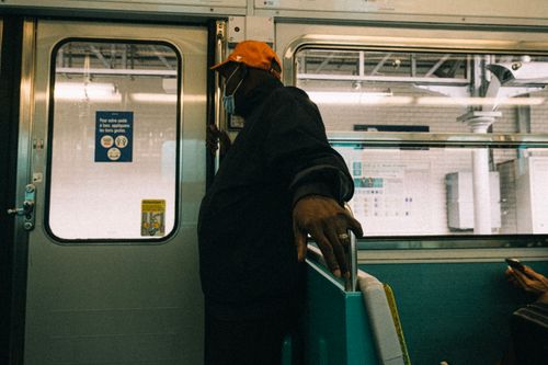 Free Man wearing a face mask standing in a train, emphasizing safety and travel during COVID-19. Stock Photo