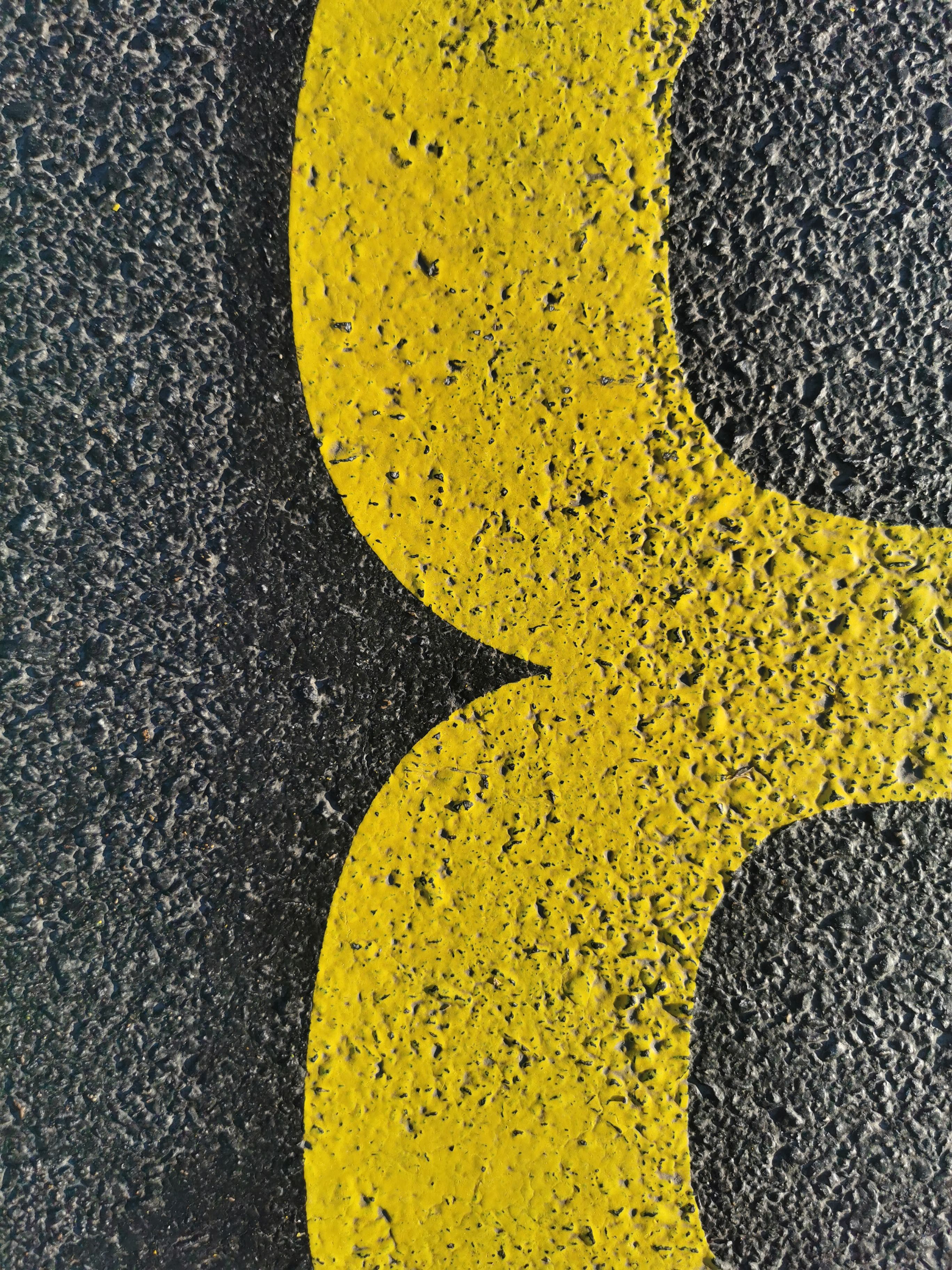 Detailed view of a yellow road marking on rough asphalt surface. Urban texture concept.