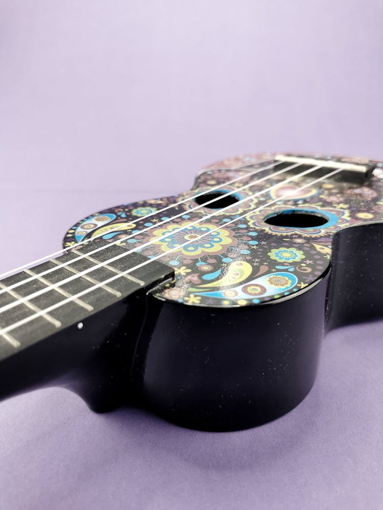 Studio Shoot Of An Acoustic Guitar With Decorative Pattern On A Lilac Background