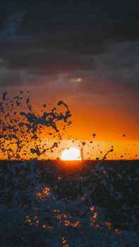 Dramatic sunset over ocean water with splashes and vivid colors inspiring awe and serenity.