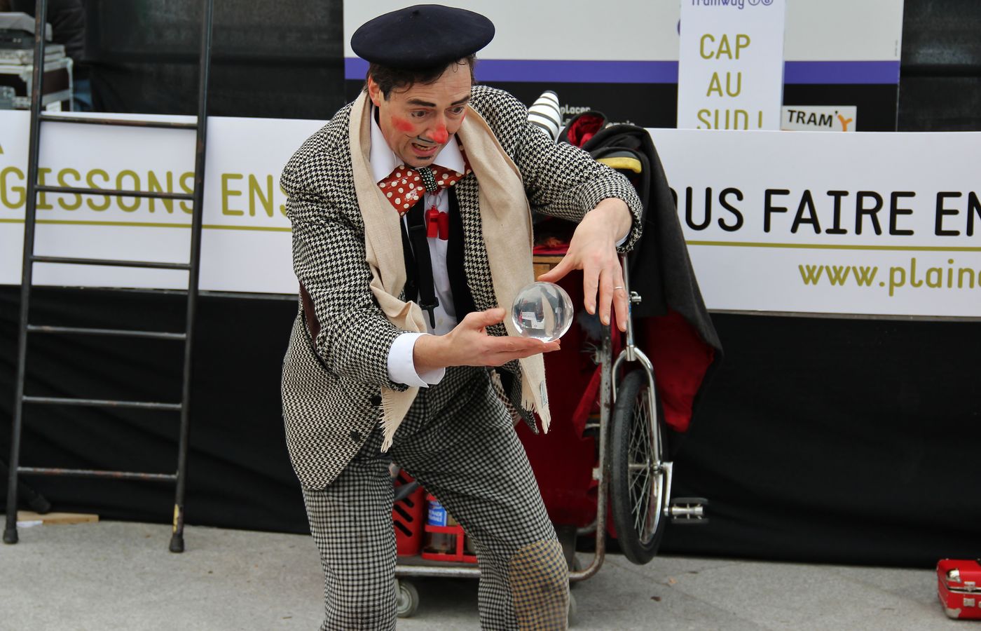 A street clown performs a captivating crystal ball act, engaging the audience.