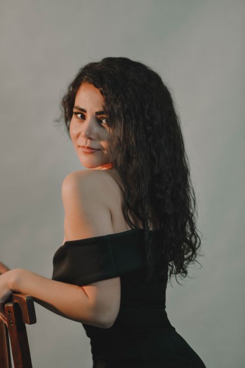 Free Charming portrait of a woman in an elegant off-shoulder black dress posing gracefully. Stock Photo