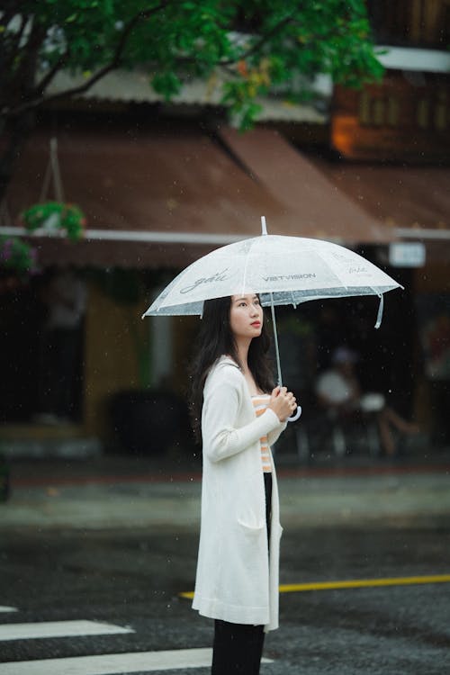 A Woman Crossing the Road while Holding an Umbrella · Free Stock Photo