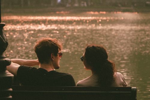 Free A couple enjoys a serene sunset view by the lake in Hanoi, Vietnam. Romantic and tranquil setting. Stock Photo