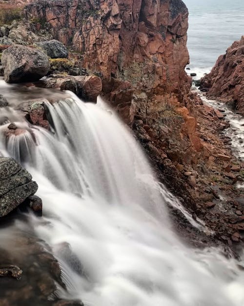 Free Waterfalls Between Brown Rocky Mountain Stock Photo