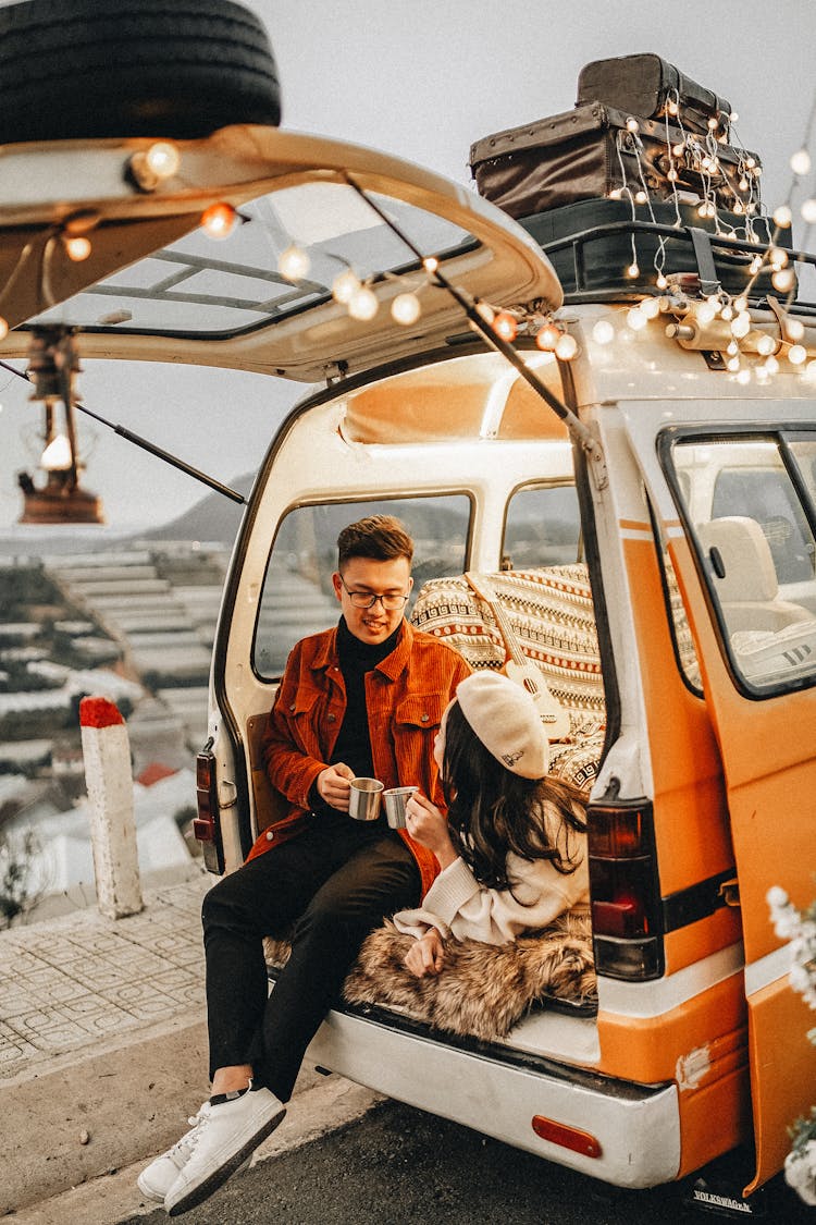 A Couple Having Coffee At The Back Of A Minivan