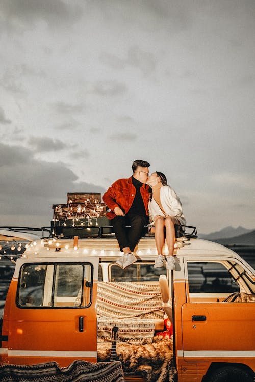 Photograph of a Couple Kissing on Top of a Van