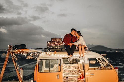 A Couple Sitting on Top of the Campervan