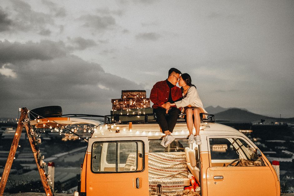 A couple shares a romantic moment on a van roof during a sunset in Dalat, Vietnam.