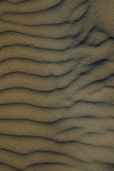 Close-up of rippling sand dunes captured from above, evoking texture and natural patterns.