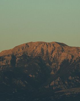 Scenic aerial shot of a rugged mountain during the day with clear skies.