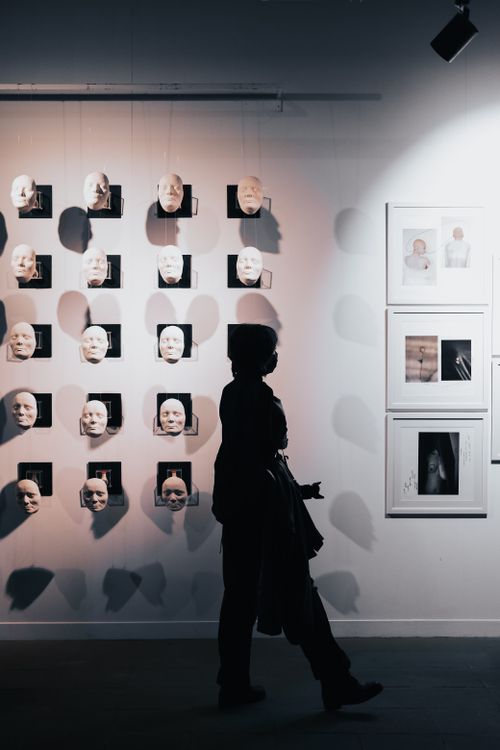 Free Silhouette of a person walking through a contemporary art exhibit with 3D faces. Stock Photo