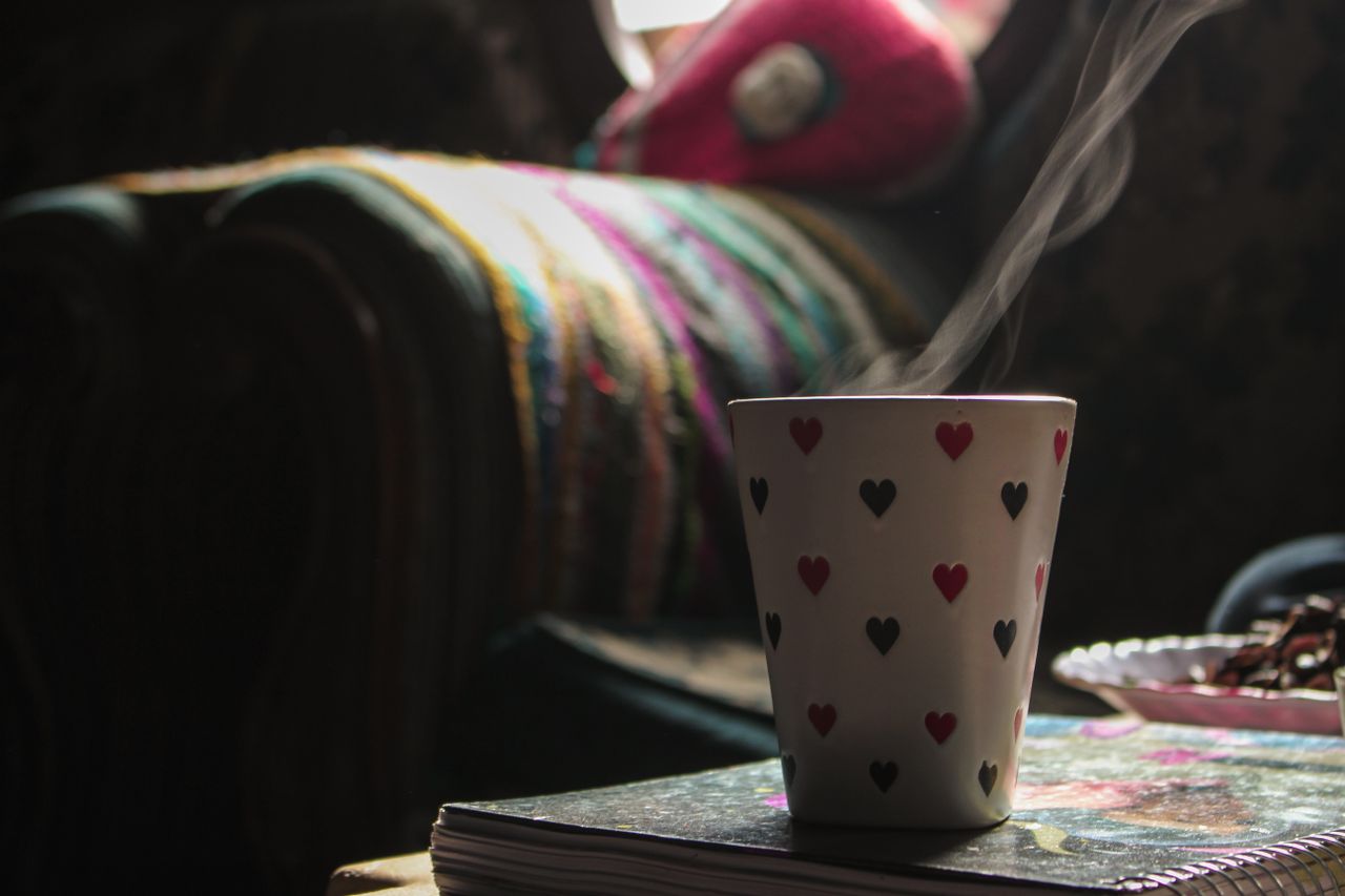 a heart patterned coffee mug releasing steam in a cozy indoor setting