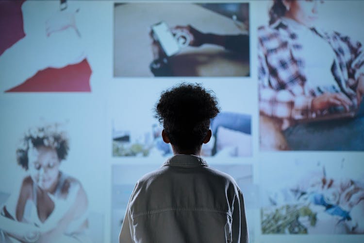 A Child Looking At Photos On Wall