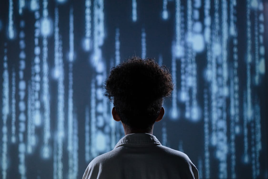 Free A young boy viewing a digital screen with data streams, symbolizing technology interaction. Stock Photo
