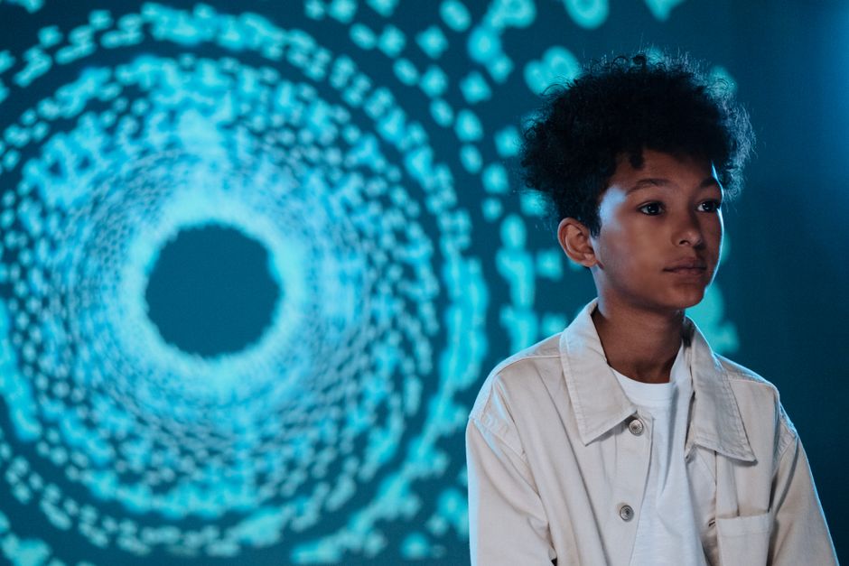 Young boy gazes thoughtfully in front of a digital abstract background.