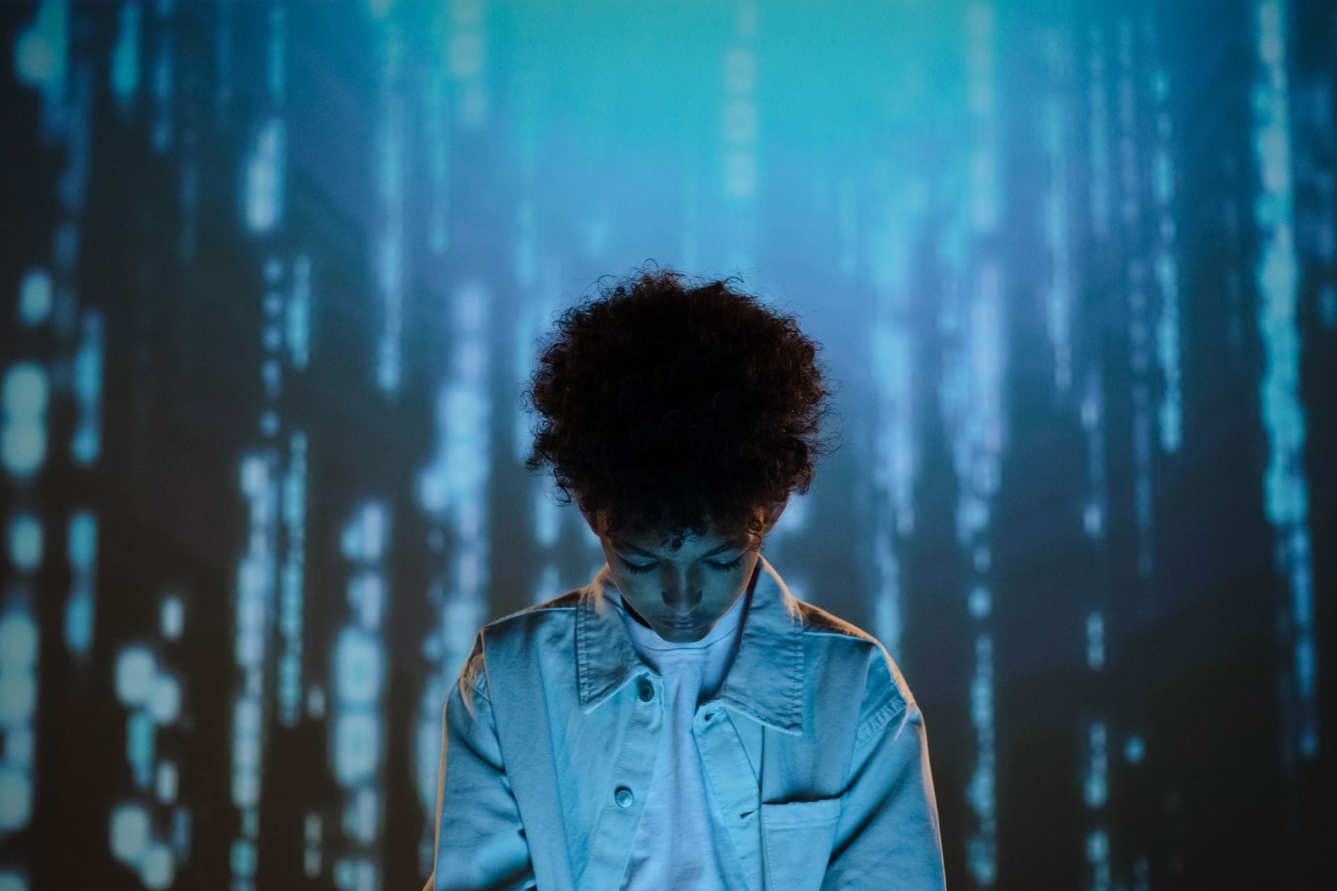 Teenage boy in a futuristic setting with digital blue background, creating a conceptual mood.