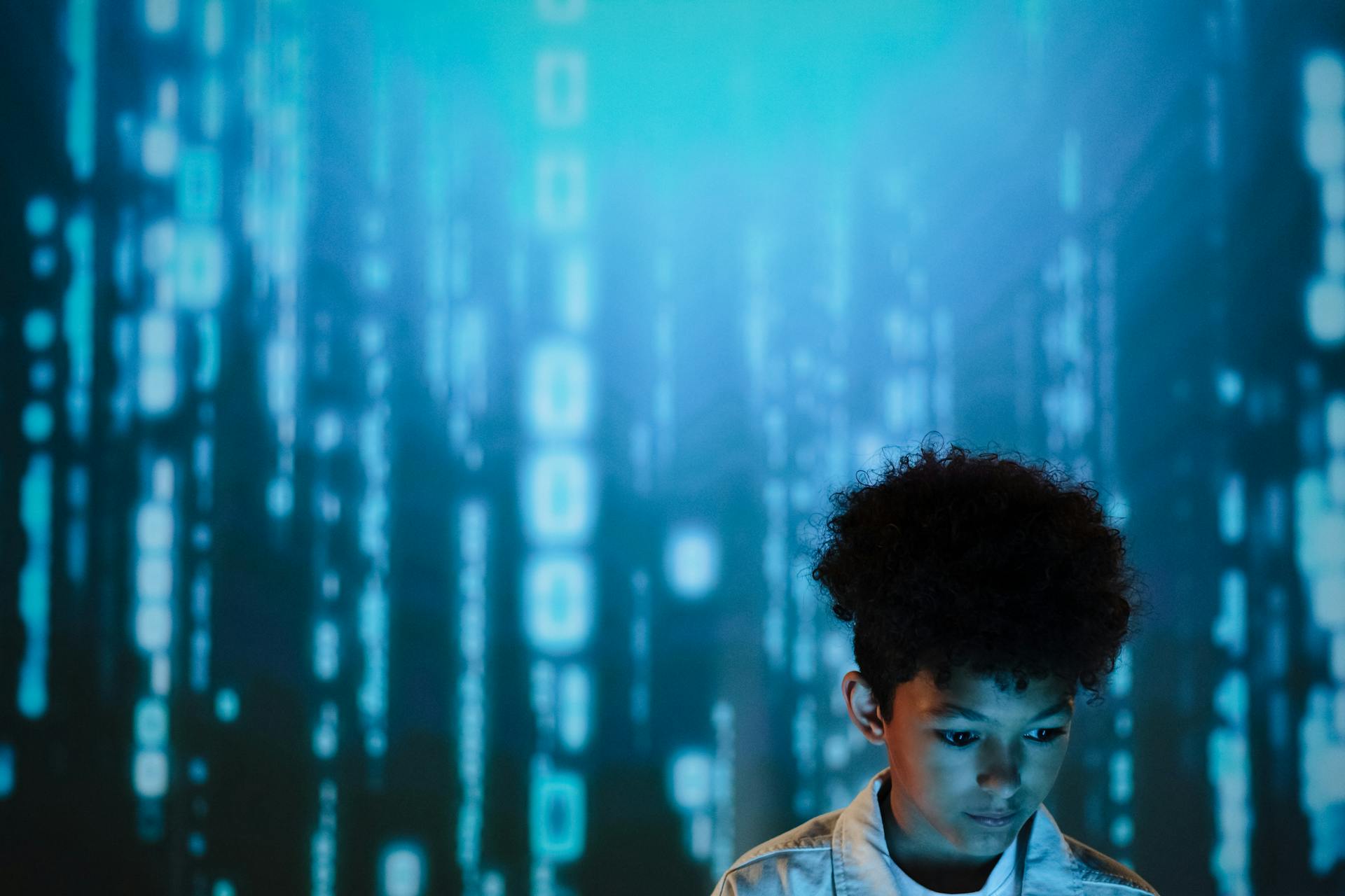 Young boy gazes at digital display creating a futuristic and modern atmosphere.