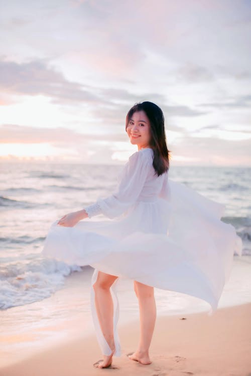 Woman in White Dress Standing on White Sand Beach
