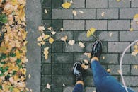 在日本长野，时尚的鞋子踩在铺满秋叶的砖砌人行道上