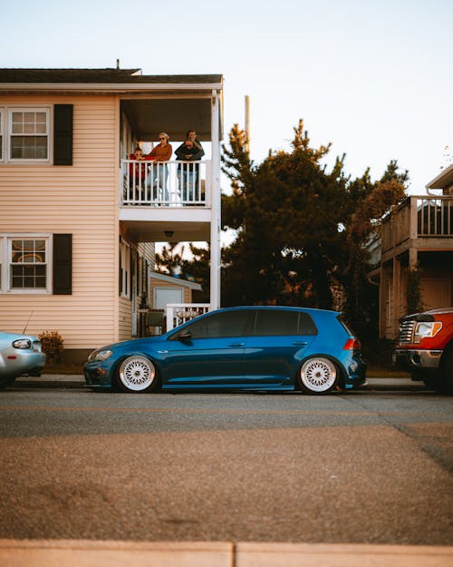 Blue Volkswagen Beetle Parked in Front of White and Brown House