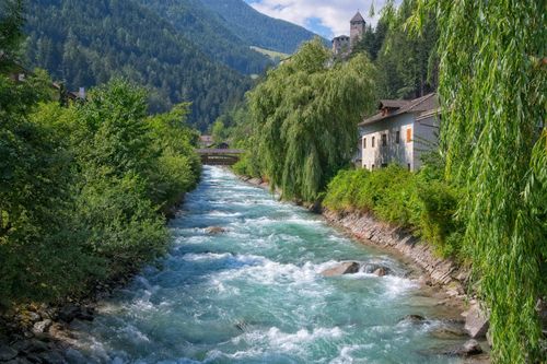 Free Peaceful river surrounded by lush greenery and mountains in Sand in Taufers, Italy. Stock Photo