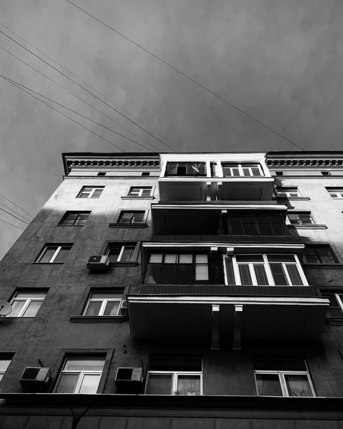 Free Monochrome low angle shot of an urban apartment building with balconies and windows. Stock Photo