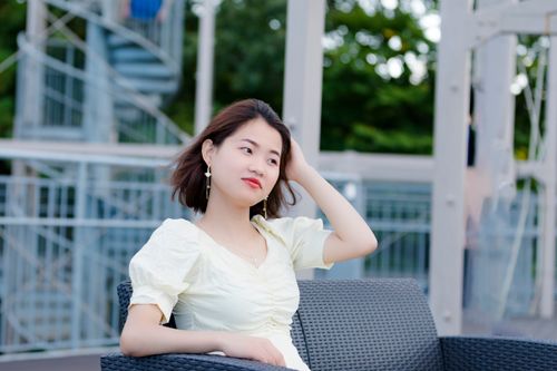 Free Asian woman sitting outdoors with a hand on her head, enjoying a moment of relaxation. Stock Photo