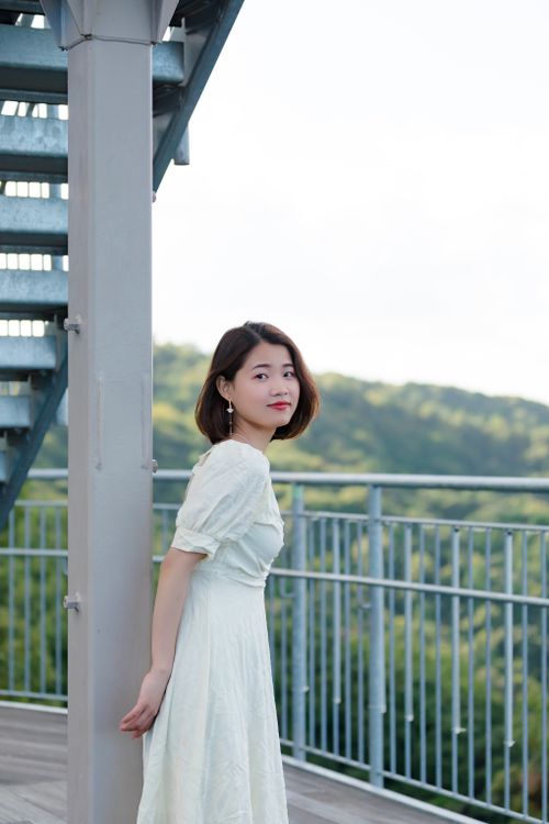 Free Charming young woman in a white dress posing outdoors, exuding elegance and style. Stock Photo