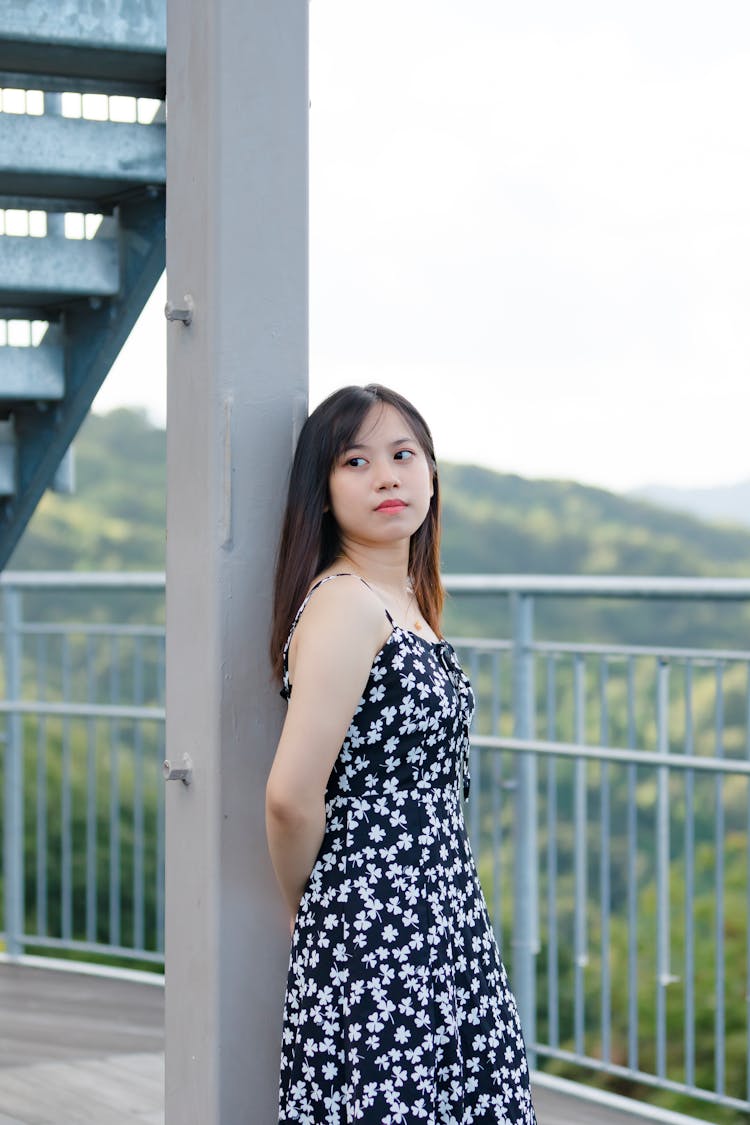 Young Girl Leaning On Metal Pole Near Railings