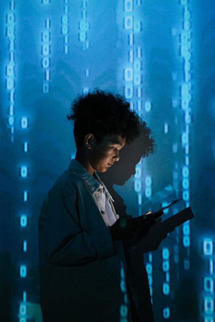 Boy Holding Tablet Beside Blue Screen