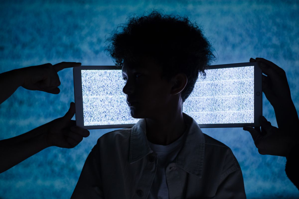 Boy sitting beside two large computer monitors illustrating excessive digital screen exposure.