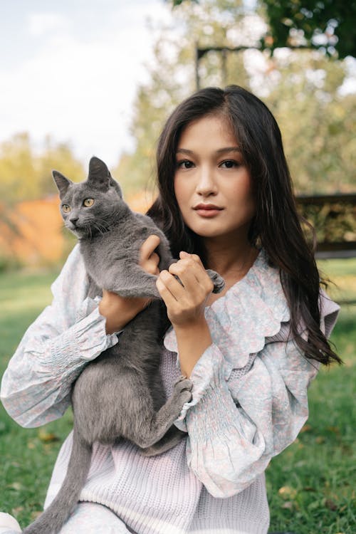 Woman in Gray Long Sleeve Shirt Holding Russian Blue Cat