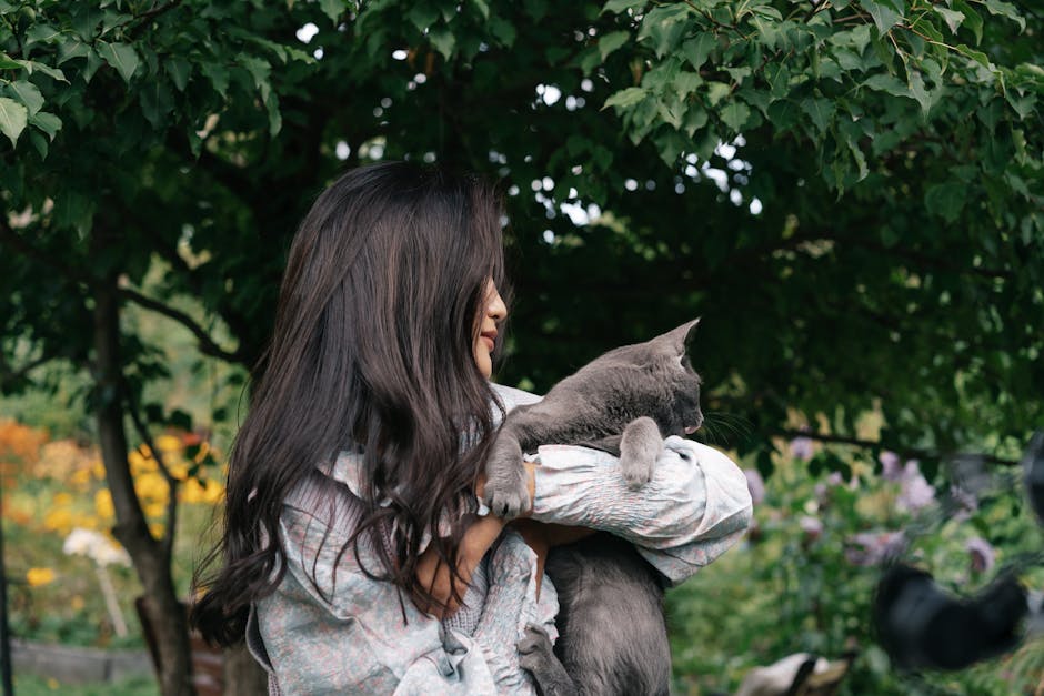 Woman in Gray Long Sleeve Shirt Carrying Russian Blue Cat