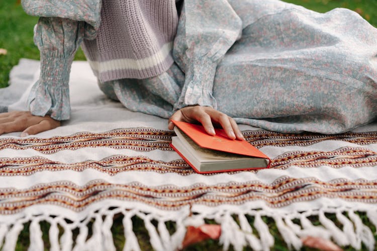 Person Wearing A Floral Dress Holding A Book