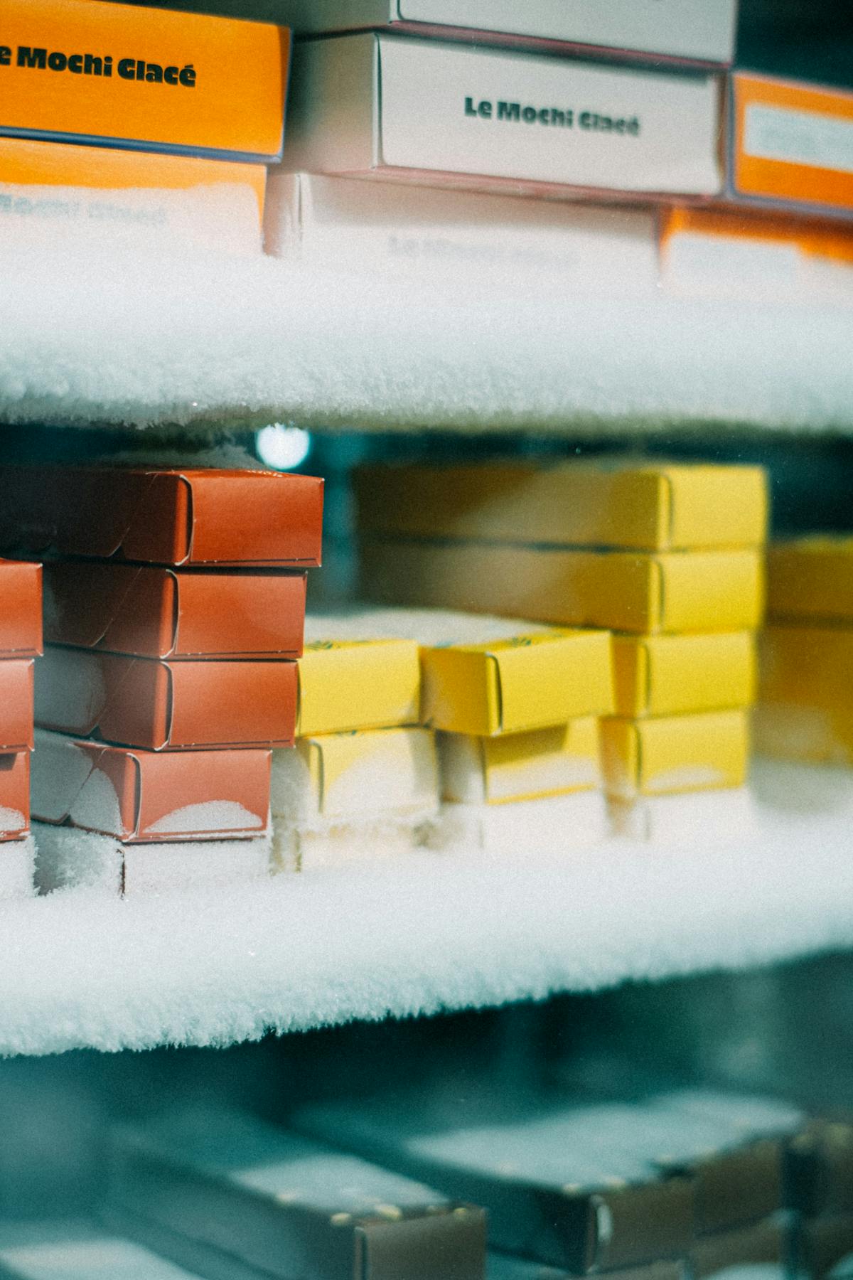 Scatole di mochi gelato impilate in freezer con brina sul vetro