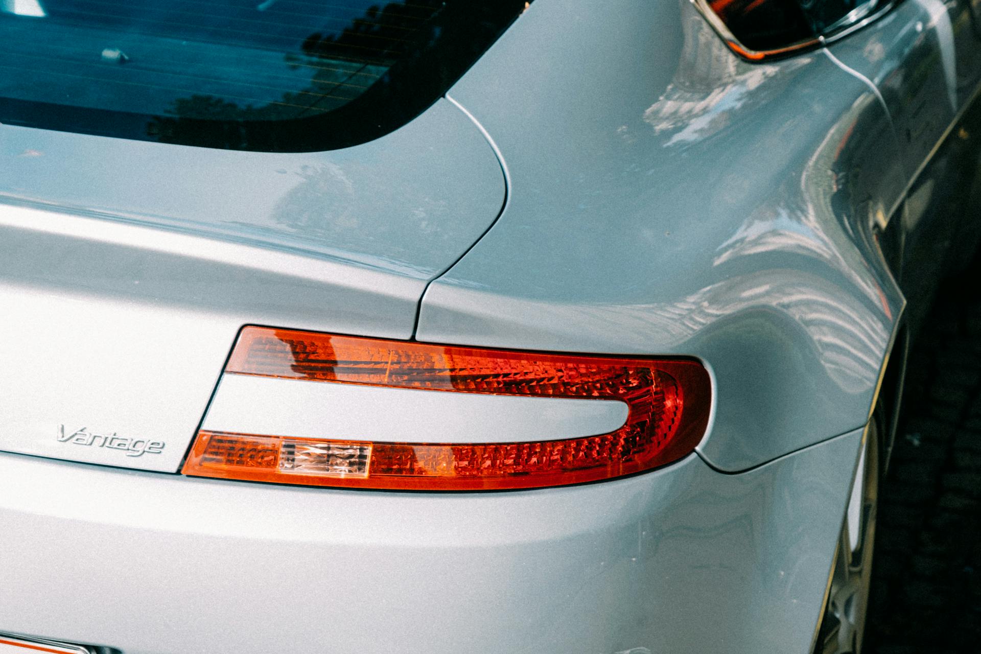 Close-up of a luxury car's rear with vivid tail light and sleek design in daylight.