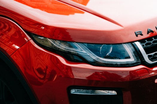 Detailed close-up of a red SUV showcasing its sleek headlight design and glossy finish.