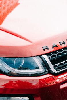 Detailed shot of a red Range Rover highlighting the headlight and grill.