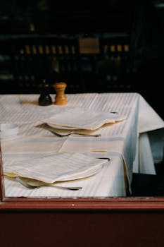 An inviting table set with white napkins and cutlery in a dimly lit restaurant.