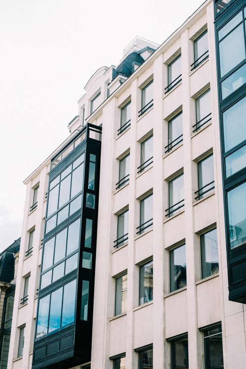 Free Low-angle view of a contemporary city building with glass and stone facade. Stock Photo