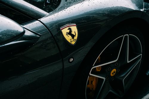Free Detailed shot of a Ferrari fender with emblem and raindrops, showcasing luxury and design. Stock Photo