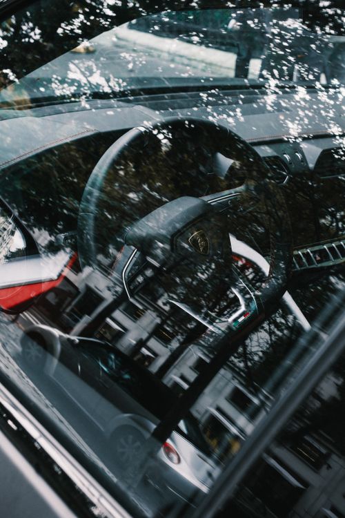 Free Close-up view of a Lamborghini steering wheel through the car window with reflections. Stock Photo