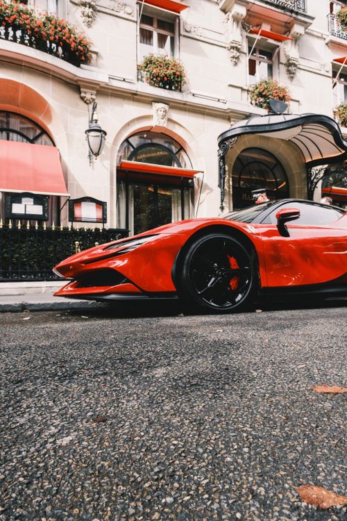 Free Eye-catching red supercar parked outside a historic building in a city setting, showcasing elegance and speed. Stock Photo